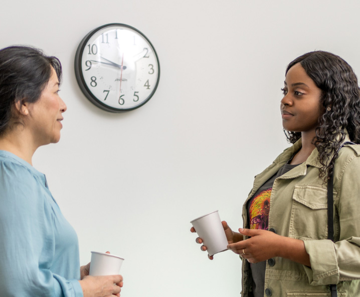 Two women chatting in front of a clock